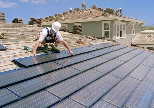 Technician installing solar panels on a residential roof